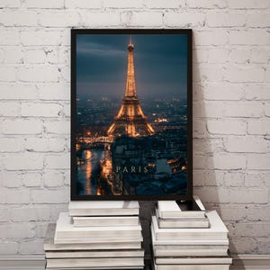 May include: A framed wall art print featuring a night view of the Eiffel Tower in Paris, illuminated with warm golden lights against a dark blue twilight sky. The word PARIS is printed in gold capital letters at the bottom of the image.
