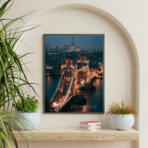 May include: A rectangular wall art print featuring a night view of Tower Bridge in London, illuminated with warm golden lights against a dark blue twilight sky. The word LONDON is printed in gold capital letters at the bottom of the image.