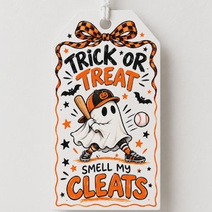 May include: A white rectangular gift tag with a string, featuring a ghost wearing a baseball cap and holding a bat. The text reads TRICK OR TREAT SMELL MY CLEATS. The design includes orange and black accents, stars, bats, and a baseball.