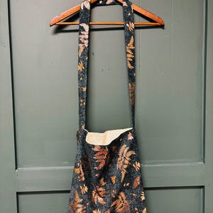 Bolso de mano verde bosque con hojas y mariposas metálicas rosas y doradas, forrado con bolsillo interior