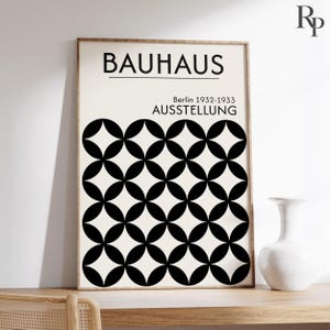 以下が含まれることがあります： 上部に「BAUHAUS」、その下に「Berlin 1932-1933 AUSSTELLUNG」と記された長方形のポスター。下部には、黒い円が重なり合って菱形のグリッドを形成する幾何学的な繰り返し模様が、クリーム色の背景に描かれています。