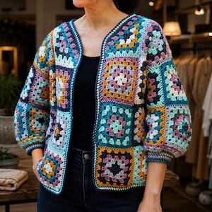 May include: A long-sleeve open-front cardigan constructed from multi-colored crochet granny squares. The garment features a vibrant palette of teal, mustard yellow, lavender, navy blue, and white, finished with a dark navy blue crochet border.