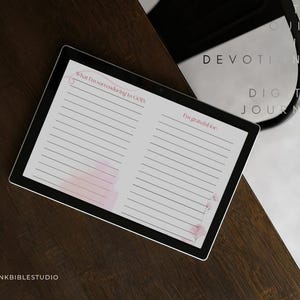 Pode incluir: Um tablet digital exibindo uma página de diário de duas colunas com detalhes em rosa. A coluna esquerda é intitulada What I'm surrendering to GOD: e a direita I'm grateful for:. Ambas as colunas possuem linhas horizontais para escrita.