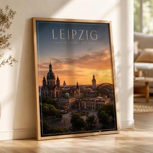 May include: A framed vertical wall art print featuring a sunset cityscape of Leipzig, Germany. The image displays historic architecture, including a prominent domed church, under a warm orange and blue sky. The text LEIPZIG GERMANY is at the top.