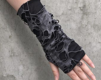 May include: A fingerless arm warmer featuring a black base layer made of a smooth, stretchy fabric, overlaid with a distressed, charcoal gray fabric that has numerous irregular holes and frayed edges throughout the entire length of the sleeve.
