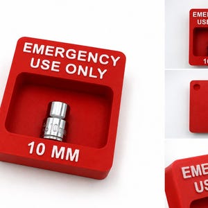May include: A red rectangular wall-mounted holder featuring a recessed centre containing a silver 10 mm socket. The holder displays the white embossed text EMERGENCY USE ONLY at the top and 10 MM at the bottom. The back includes two keyhole slots.