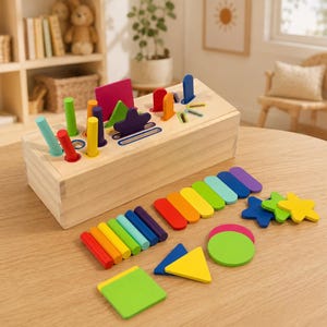 May include: A wooden sorting box with a natural finish featuring various slots and holes on the top surface. Included are numerous colorful wooden shapes, including cylinders, rectangles, triangles, stars, and circles in shades of red, orange, yellow, green, blue, and purple.