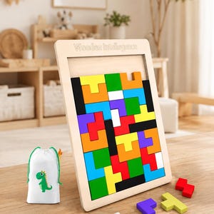 Op de afbeelding: Een houten puzzelbord met de tekst "Wooden Intellegence" bovenaan gegraveerd, gevuld met diverse kleurrijke geometrische blokken. Een witte tas met trekkoord en een groene dinosaurusafbeelding en enkele losse puzzelstukjes liggen ernaast.