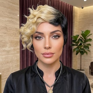 以下が含まれることがあります： プラチナブロンドのウェーブヘアとストレートの黒髪を左右で組み合わせた、ツートンカラーのショートレイヤーウィッグ。サイドパートの非対称なカットが特徴で、顔周りに柔らかくボリュームのあるウェーブがかかっています。