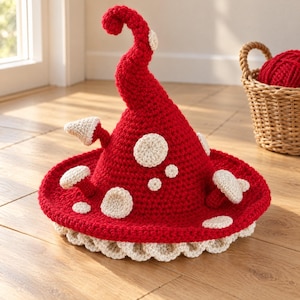 May include: A red crocheted hat with a tall, curled point and a wide brim. The hat is decorated with several cream-colored, three-dimensional mushroom-shaped appliqués and flat circular spots. The bottom edge features a ruffled cream trim.