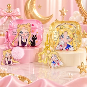 May include: Two protective cases for wireless earbuds featuring Sailor Moon graphics. The pink case shows Sailor Moon and a black cat with a pink pom-pom charm. The yellow case features Sailor Moon drinking from a cup with the text CUTE DAILY MOMENTS.