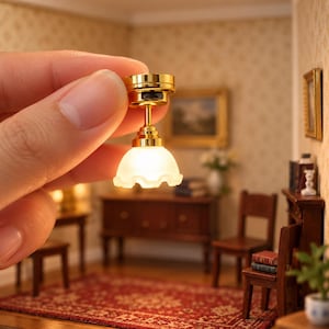 Könnte beinhalten: Eine Miniatur-Deckenleuchte mit einem polierten, goldfarbenen Metallsockel und einem kleinen, gewellten, mattweißen Glasschirm, der ein warmes, sanftes Licht abgibt. Die kompakte Lampe hat ein schlichtes Design für Puppenhausbeleuchtung.