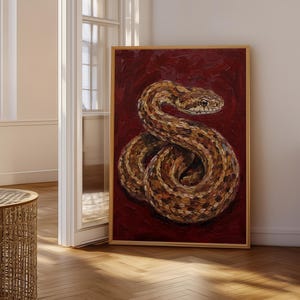 May include: A rectangular framed painting featuring a coiled snake with brown, tan, and black scales. The snake is positioned against a deep, textured dark red background. The artwork is enclosed in a thin, light-coloured wooden frame.