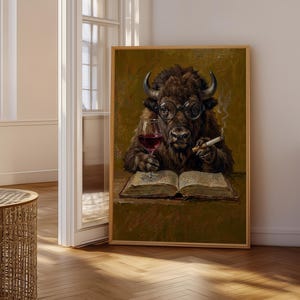 Può includere: Una stampa artistica incorniciata raffigurante un bisonte marrone con occhiali tondi, che tiene un bicchiere di vino rosso in una mano e un sigaro acceso nell'altra, mentre legge un libro aperto. Lo sfondo è verde oliva scuro e la cornice è in legno chiaro.