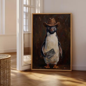 Könnte beinhalten: Ein gerahmtes Ölgemälde, das einen Pinguin mit einem braunen Cowboyhut zeigt, der ein silbernes Hackmesser hält. Der Pinguin ist vor einem dunklen, strukturierten braunen Hintergrund mit sichtbaren Pinselstrichen in einem Goldrahmen dargestellt.