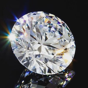 May include: A round brilliant cut diamond with numerous triangular and kite-shaped facets. The gemstone is clear and colorless, exhibiting intense light refraction with bright white highlights and subtle rainbow-colored spectral light flares.