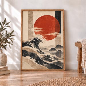 May include: A framed wall art print featuring a large red sun centered above stylized dark blue ocean waves. The composition includes vertical rectangular panels in beige and dark gray, with a textured, weathered appearance throughout the artwork.