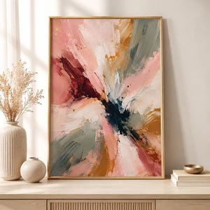 May include: A rectangular wall art piece in a thin gold frame featuring an abstract painting with bold, expressive brushstrokes in shades of dusty pink, deep burgundy, muted sage green, ochre, and white, radiating from a dark central point.