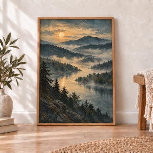 Op de afbeelding: Een ingelijste landschapsafdruk met een kronkelende rivier die bij zonsopgang door een dicht dennenbos stroomt. De scène bevat mistige bergen op de achtergrond onder een gouden lucht, met rotsachtig terrein op de voorgrond.
