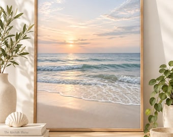 Puede incluir: Una impresión de arte mural enmarcada rectangular que muestra un paisaje de playa sereno al amanecer. La imagen presenta nubes de tonos pastel suaves, un océano tranquilo con olas suaves en la orilla y un cálido resplandor dorado en el agua.