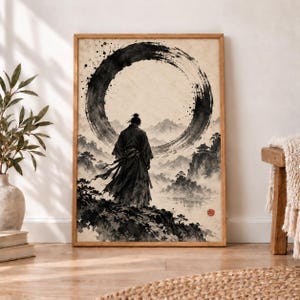 May include: A framed wall art print featuring a black ink wash painting of a figure in traditional robes standing on a cliff edge, looking toward a large circular brushstroke against a backdrop of misty mountains and a small pagoda.