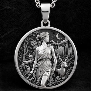 May include: A circular silver pendant necklace featuring a detailed relief of a figure holding a bow and arrows, accompanied by a deer in a forest setting with a crescent moon and stars in the background. The design is rendered in polished silver.