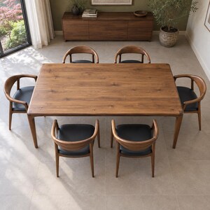 Elevated long-side view showing the tabletop and symmetrical chair arrangement. Styled with walnut chairs and black seats. This listing includes the dining table only; chairs and decorative accessories are not included.