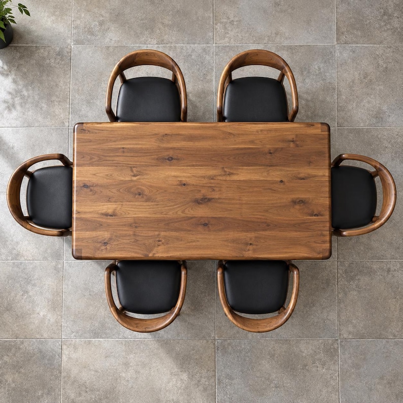 Top-down view of the walnut tabletop with six surrounding chairs on a ceramic floor. Styled with walnut chairs and black seats. This listing includes the dining table only; chairs and decorative accessories are not included.