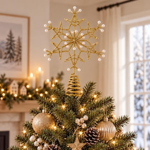 May include: A gold glittery snowflake tree topper featuring a spiral base and white pearl accents at the tips and centre. The snowflake design is intricate with multiple points, providing a decorative finish for the top of a Christmas tree.