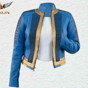 May include: A blue jacket featuring a stand-up collar, long sleeves, and a front zipper closure. The design includes gold-colored trim along the front opening and hem, with dark blue ribbed panels on the shoulders and chest area. The Averon logo is visible.