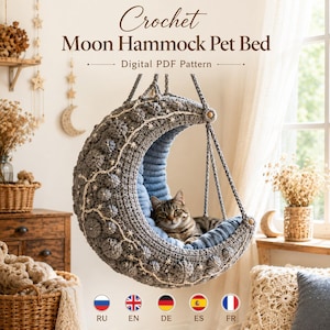 May include: A gray crochet moon-shaped hanging pet bed with a textured surface and white star embroidery. A brown tabby cat rests inside the hammock. The text reads Crochet Moon Hammock Pet Bed Digital PDF Pattern with language icons below.