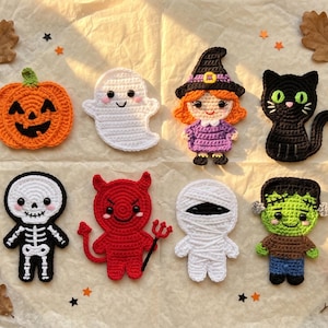 May include: A collection of eight crocheted Halloween-themed appliqués including an orange pumpkin, a white ghost, a witch, a black cat, a skeleton, a red devil with a pitchfork, a white mummy, and a green monster, all arranged on a crinkled paper.