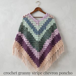 May include: A crochet poncho featuring a chevron pattern with horizontal stripes in shades of lavender, mint green, dark teal, deep purple, and beige. The garment has a V-neckline and is finished with long fringe along the bottom hem.