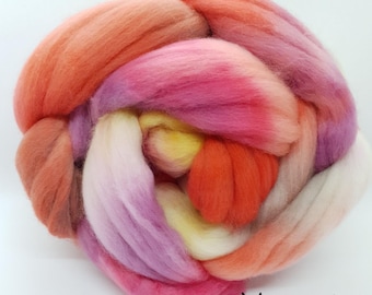 May include: A close-up of a bundle of colorful wool roving in shades of pink, orange, yellow, and white. The roving is arranged in a loose braid and the colors blend together seamlessly. The word "Memories" is written in black text at the bottom of the image.