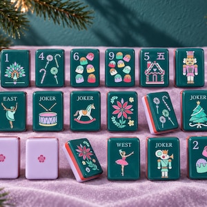 May include: A set of rectangular mahjong tiles in dark green and light purple. The green tiles feature colorful holiday-themed illustrations including a nutcracker, Christmas tree, gingerbread house, candy canes, and dancers. Some tiles display numbers or text like East, West, and Joker.