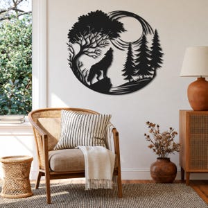 May include: A circular black metal wall art piece featuring a silhouette of a wolf howling at a full moon. The design includes a large deciduous tree on the left, three pine trees on the right, and a rocky outcrop where the wolf is standing.