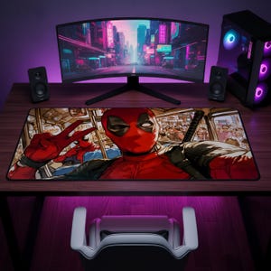 May include: A rectangular desk mat featuring a graphic illustration of the character Deadpool taking a selfie on a crowded bus. The character wears a red and black suit and makes a peace sign with one hand. The background shows passengers on a bus.