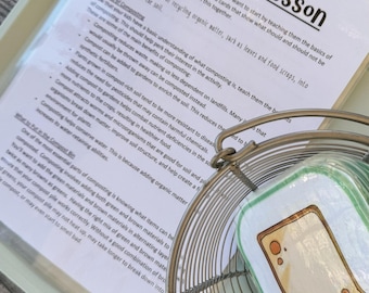 Puede incluir: Una hoja educativa Composting Lesson con texto negro sobre papel blanco, junto a una cesta de alambre circular que contiene una tarjeta plastificada con una ilustración de una rebanada de pan con cara y manchas marrones.