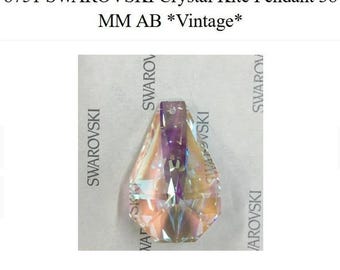 May include: A Swarovski crystal kite pendant, approximately 38 mm in size, with an AB (Aurora Borealis) finish. The crystal is faceted, reflecting a spectrum of colors. The text "8751 SWAROVSKI Crystal Kite Pendant 38 MM AB *Vintage*" is visible.