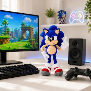 Può includere: Una bambola realizzata all'uncinetto a mano del personaggio Sonic the Hedgehog, con un corpo blu brillante, muso e pancia color sabbia, guanti bianchi e scarpe da ginnastica rosse e bianche. La figura è in piedi con una mano alzata e mostra punti dettagliati.