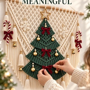 May include: A macrame wall hanging featuring a cream-colored triangular backdrop with a dark green macrame Christmas tree in the center. The tree is decorated with gold spheres, red velvet bows, and a star topper. Text reads: MAKE SOMETHING MEANINGFUL.