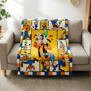 May include: A rectangular fleece blanket featuring a collage of Goofy in various poses. The centre panel shows Goofy making a peace sign with red hearts, with the text NAME printed below. The border has alternating blue and orange stripes.