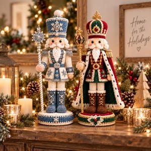Può includere: Due figure di schiaccianoci all'uncinetto su basi circolari. La figura a sinistra indossa un'uniforme blu e bianca con motivi a fiocco di neve e tiene un bastone. La figura a destra indossa un abito reale rosso e verde con una corona.