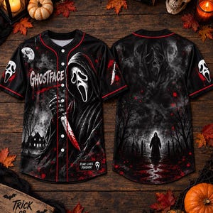 May include: A black baseball jersey featuring a Ghostface graphic with a bloody knife, the text "GHOSTFACE" and "FEAR LIVES FOREVER", and red piping. The back displays a dark forest scene with a silhouette figure and a large ghostly face overlay.
