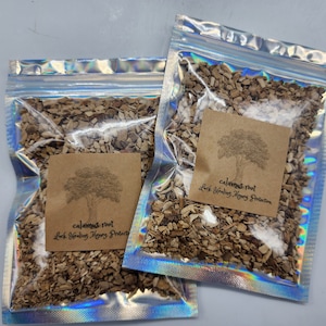 May include: Two clear resealable bags filled with dried calamus root. The bags have brown paper labels with a tree illustration and the text "calamus root, Luck Healing Money Protection".