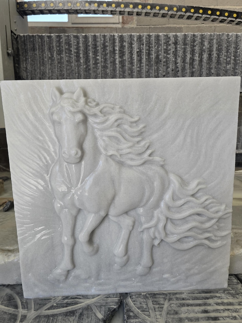 May include: A square white stone tile featuring a high-relief carving of a horse in motion. The horse is depicted facing forward with a flowing mane and tail that extend across the surface, creating a dynamic sense of movement in the stone.