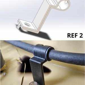 May include: A black metal Z-shaped mounting bracket with a circular clamp at one end and a flat base with a bolt hole at the other. The bracket is secured to a tan surface with a silver hex bolt. The text REF 2 appears in the upper right corner.