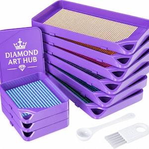 May include: A set of purple plastic diamond painting trays stacked in two columns, with one tray lid featuring the text DIAMOND ART HUB and a crown icon. The trays contain small colorful beads. A white plastic spoon and a small brush are included.