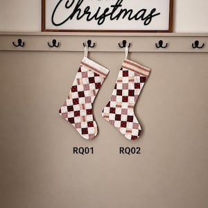 May include: Two quilted Christmas stockings featuring a red and white checkered patchwork pattern, hanging from a wooden rack. Above the rack is a sign with the text Merry Christmas. The stockings are labeled RQ01 and RQ02 in black text.