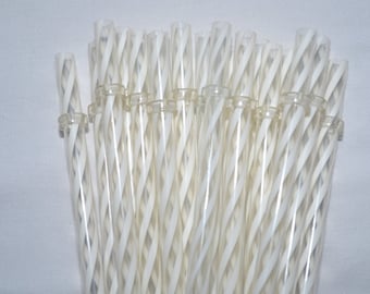 May include: A bundle of clear, transparent glass straws with a white, spiral design. The straws are held together with a clear plastic ring. The straws are approximately 8 inches long.